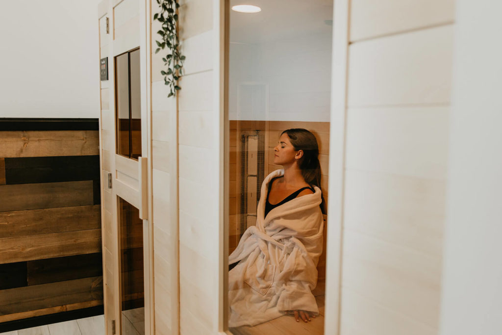 A woman relaxing in a sauna after a workout at Recovery Lab in Red Deer.