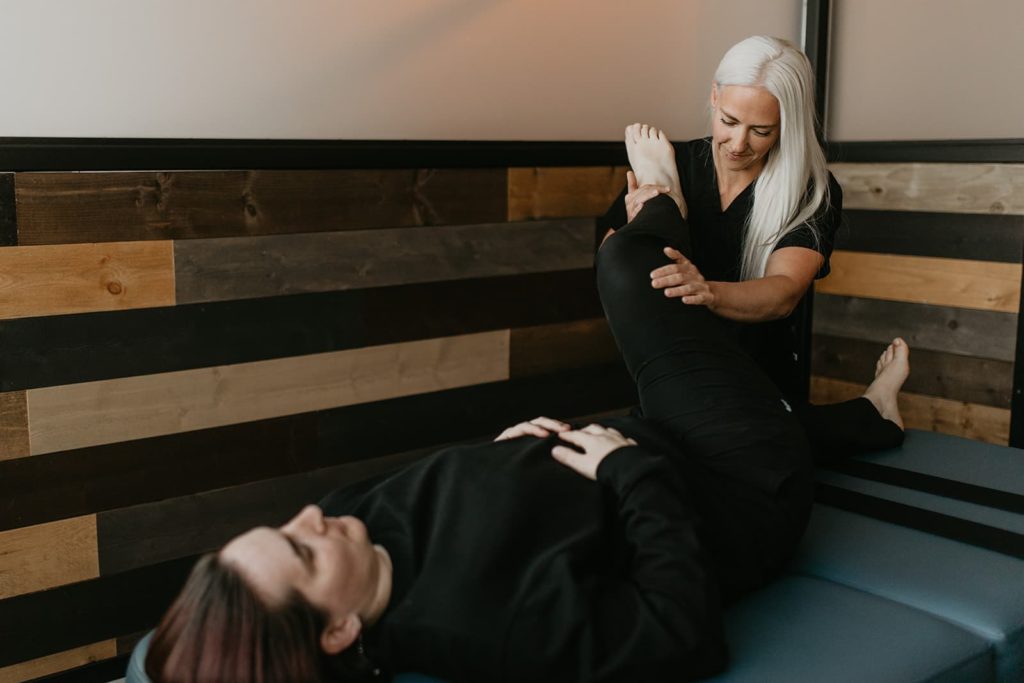 A fascial stretch therapist working on a male who has tight hip flexors and lower back pain