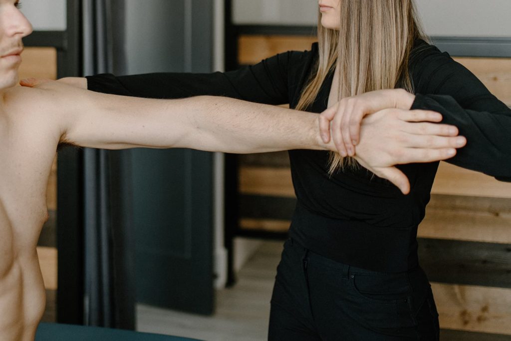 A physiotherapist working on a patients shoulder for muscle strengthening, stretching, and recovery