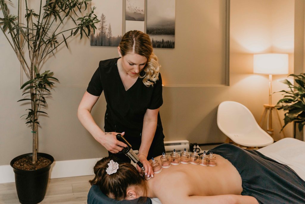 A massage therapist performing myofascial cupping therapy on a patient's back.