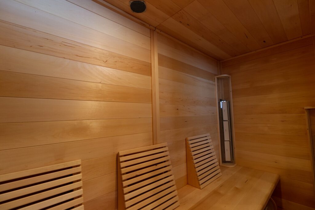 The inside of an infrared sauna at Recovery Lab in Red Deer, showing the wood inside and seating.