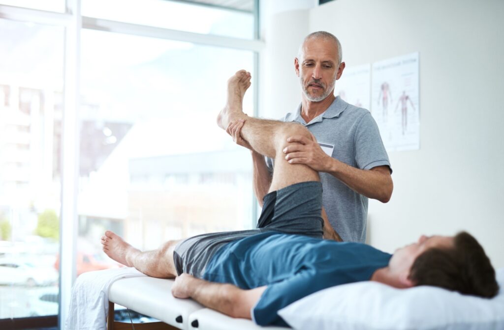 A physiotherapist holding up the knee and calf of a patient lying on a table.