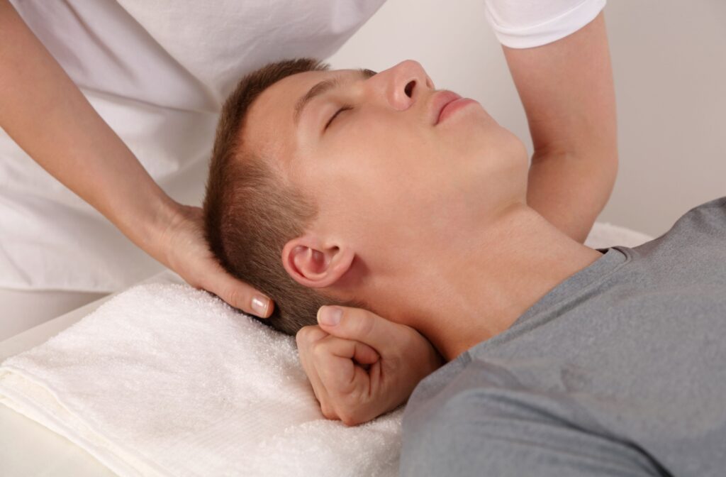 A therapist adjusts their patient's head during a craniosacral therapy session.