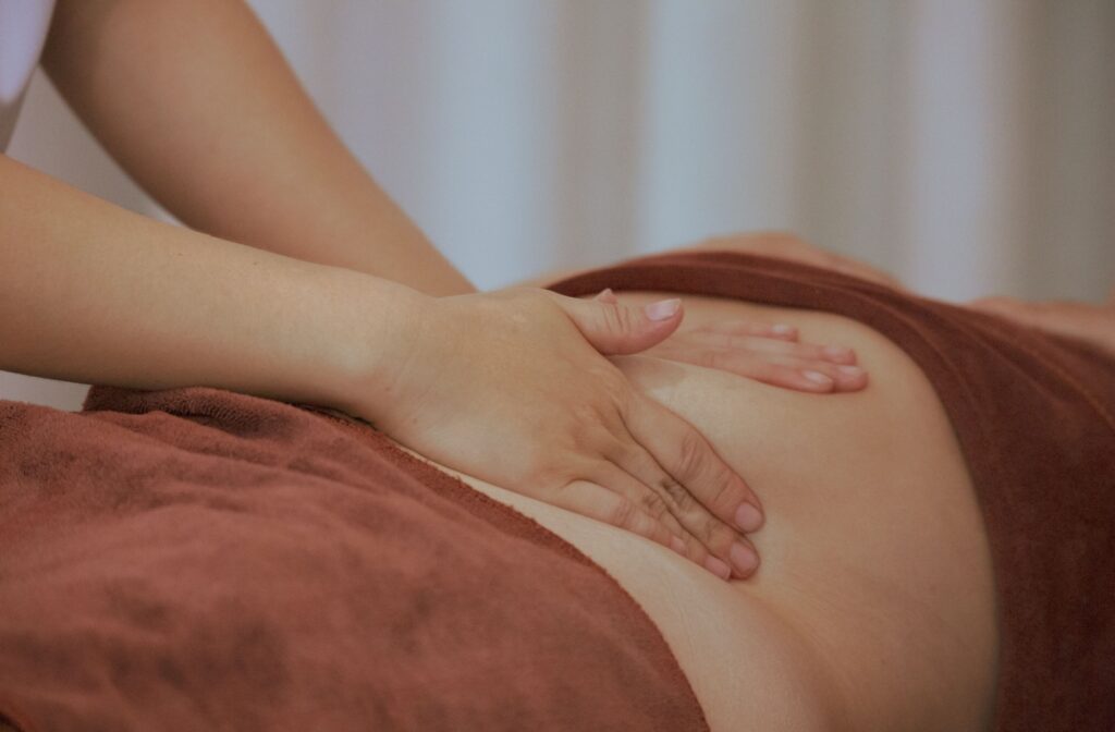 Close-up of a therapist's hands massaging a person's torso as part of lymphatic massage therapy.