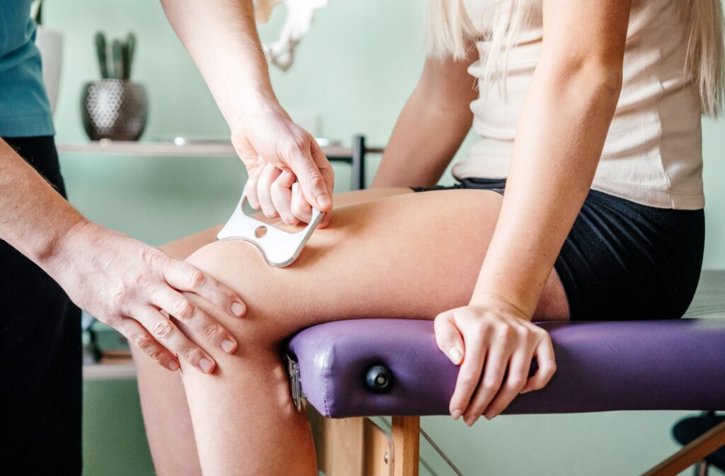 A massage therapist performs a Graston Technique massage on their patient's leg