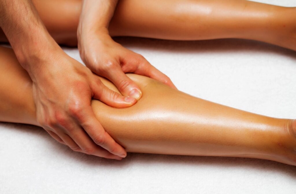 A close up of a pair of hands massage a person calf muscle