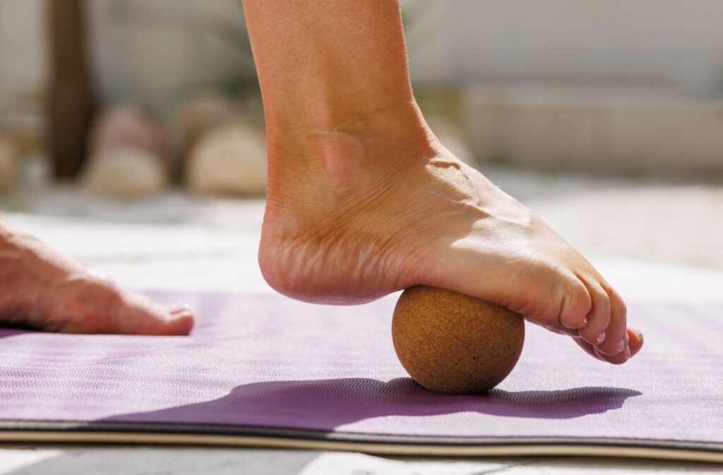 A foot using a wooden ball for relief from plantar fasciitis